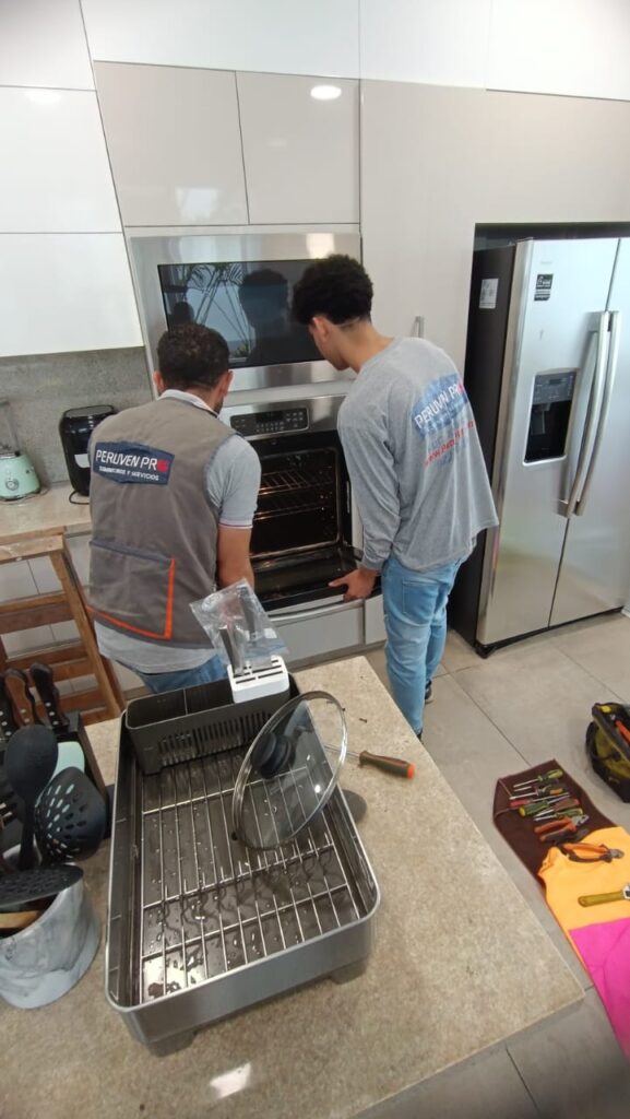 Técnicos de Peruven Pro realizando diagnóstico y mantenimiento de horno empotrado en cocina residencial