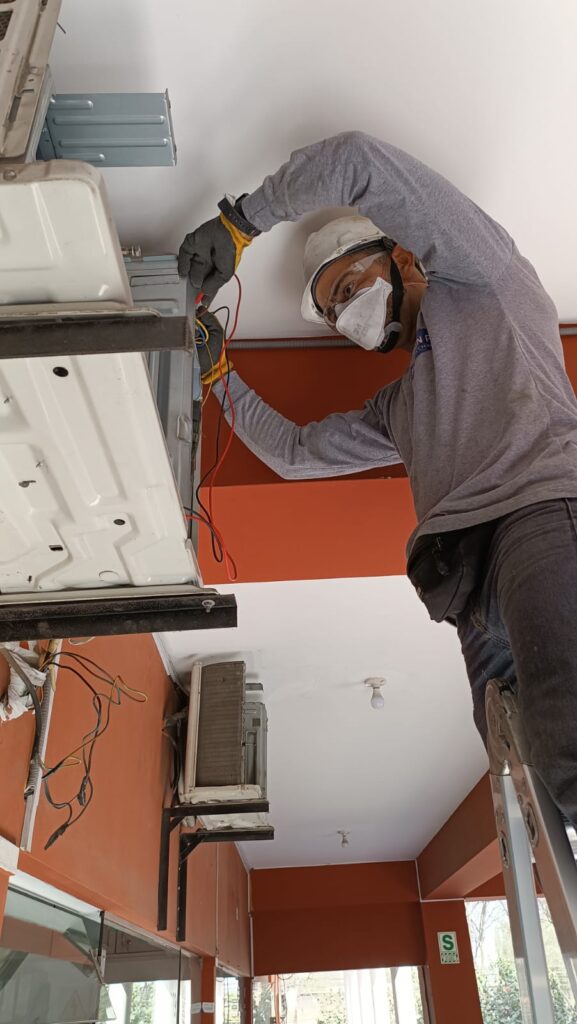 Técnico de Peruven Pro realizando instalación de aire acondicionado tipo split en local comercial