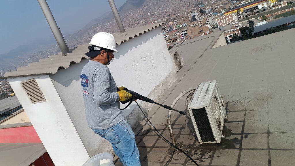 Técnico de Peruven Pro realizando limpieza de unidad exterior de aire acondicionado en azotea