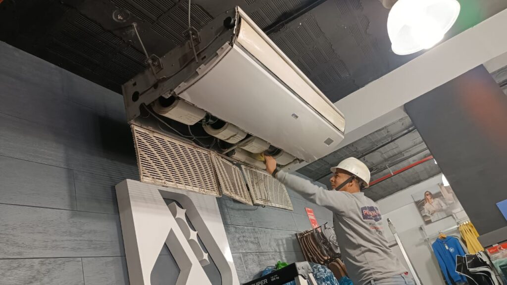 Técnico de Peruven Pro realizando mantenimiento de aire acondicionado en local comercial